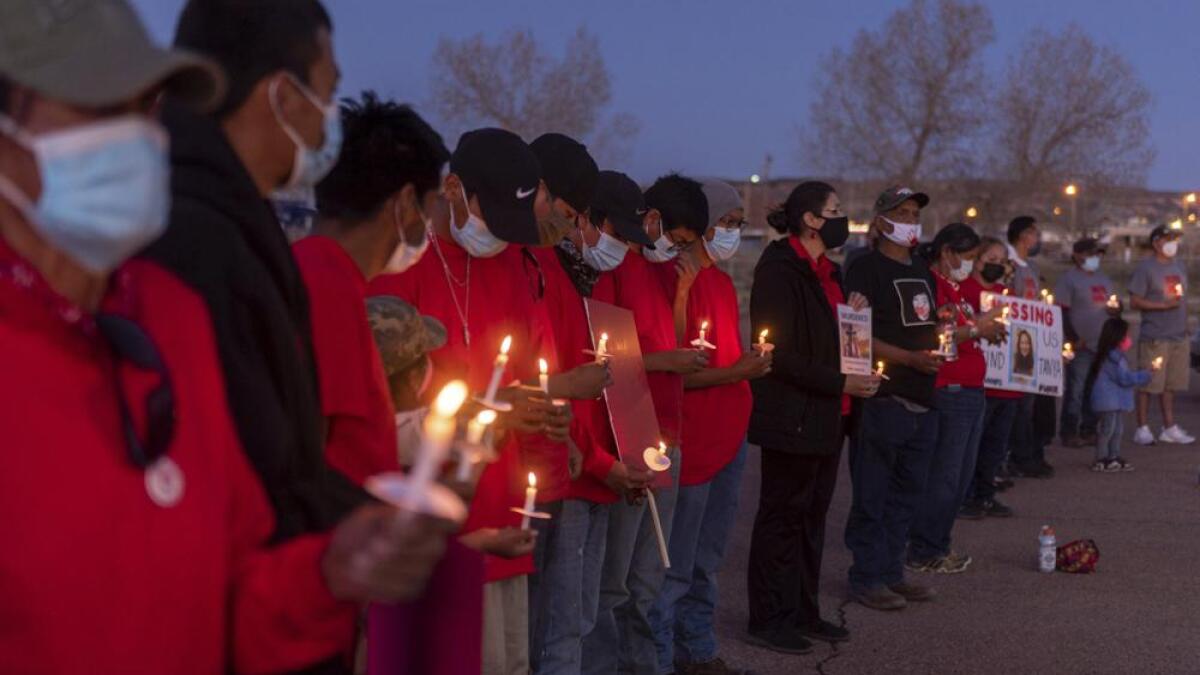 A community vigil at night with people holding candles outdoors on Navajo Nation land, standing quietly in a circle
