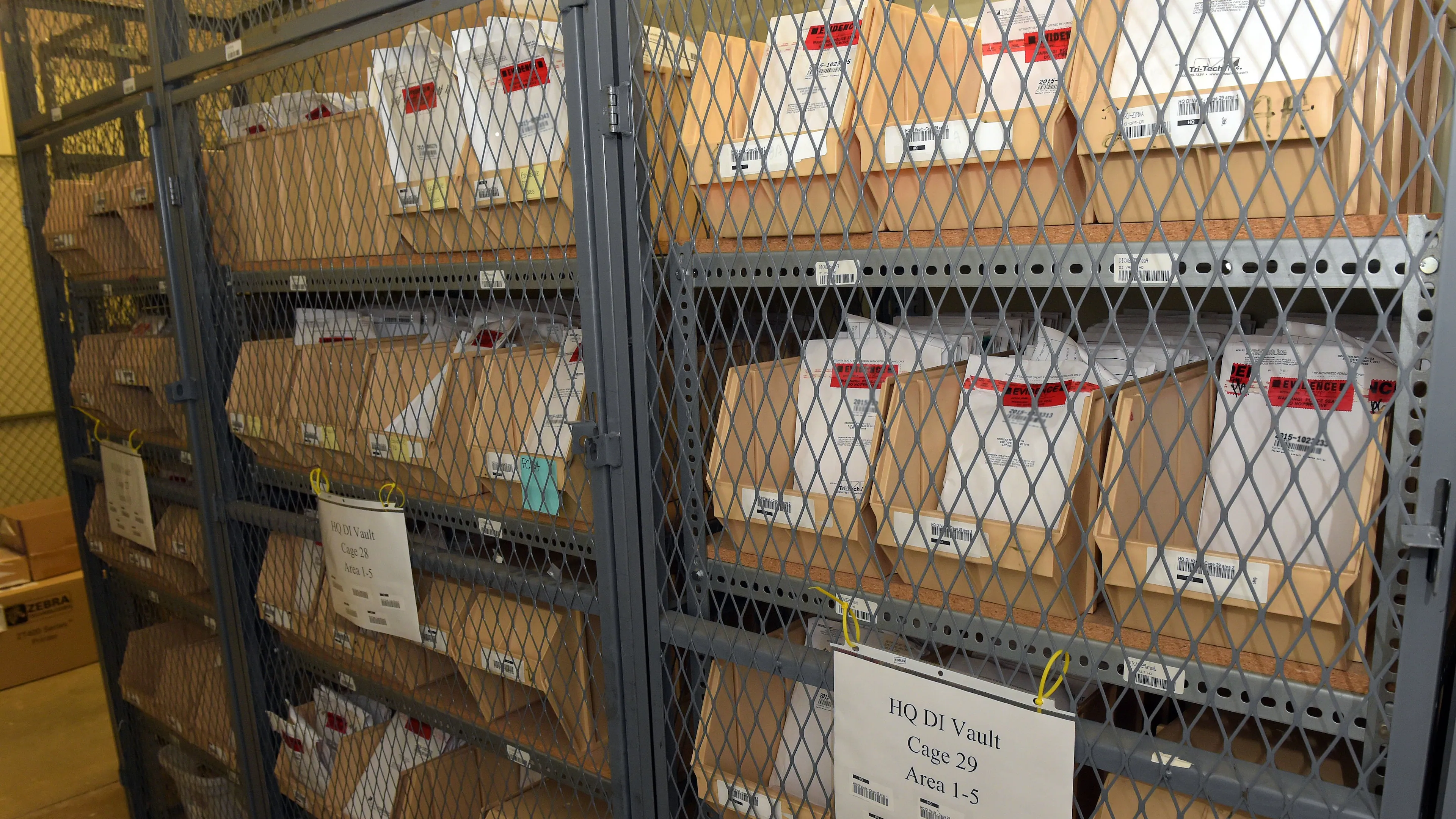 A forensic analyst in a county crime lab placing sealed evidence envelopes onto a metal shelving unit, emphasizing the slow, procedural pace of real casework