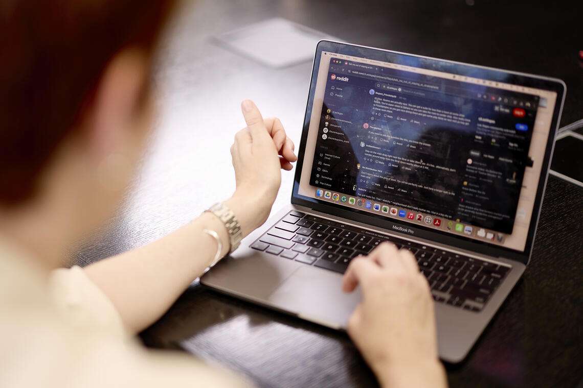 A laptop open to a long Reddit discussion thread about a criminal investigation, photographed on a desk at night with a mug nearby