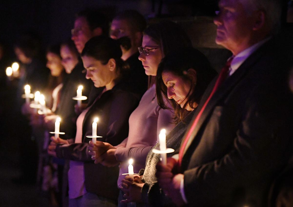 A nighttime candlelight vigil outside a community center, attendees holding candles in silence to honor victims of domestic violence