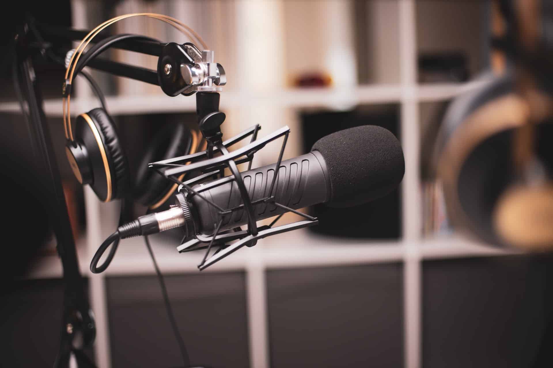 A podcast microphone on a desk beside a notebook and a cup of tea under a small lamp