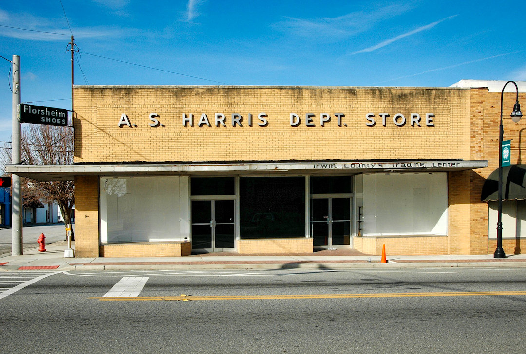 A quiet main street in Ocilla, Georgia, with small storefronts and an empty sidewalk in late afternoon light