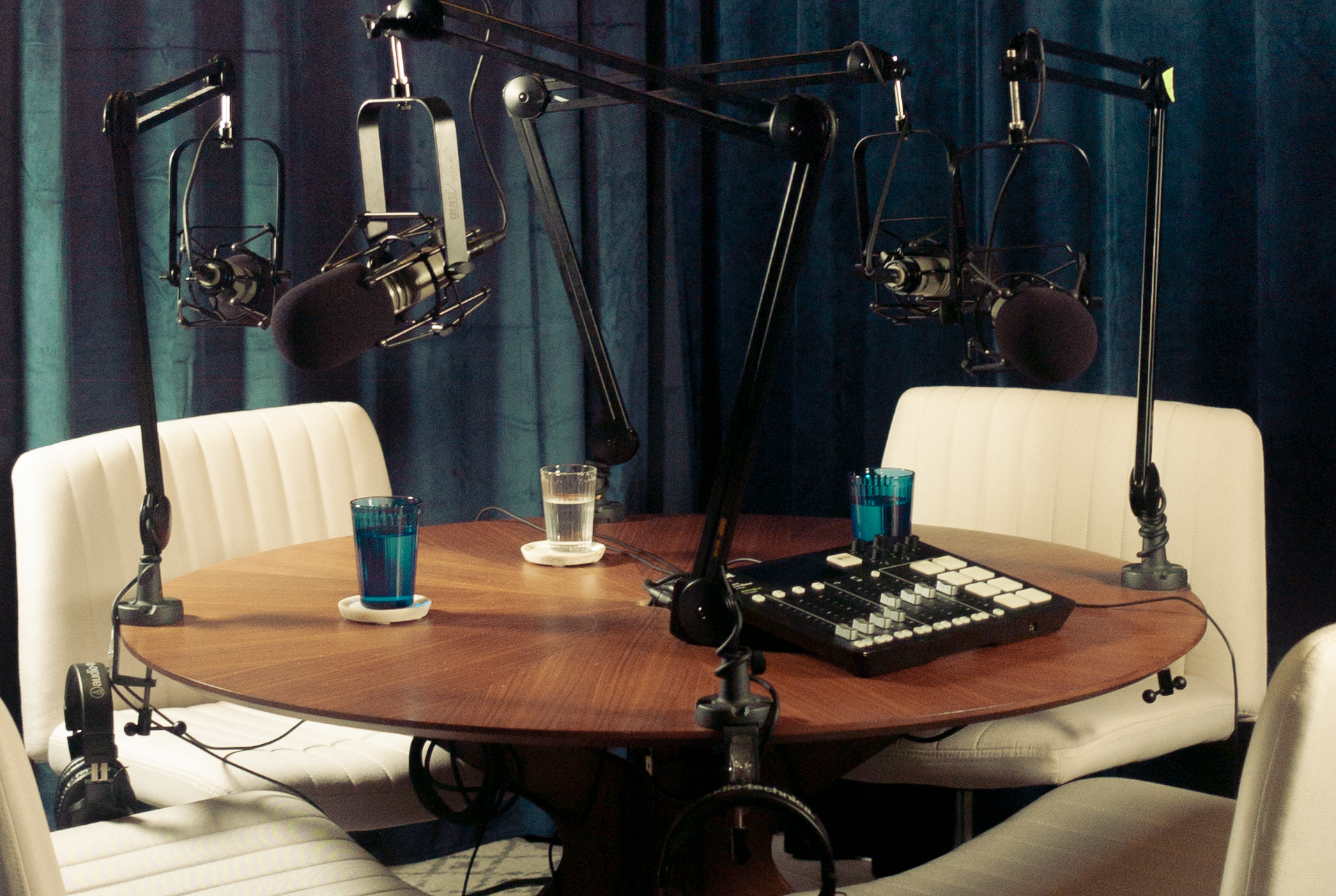 A recording studio scene with a narrator at a microphone and a producer monitoring audio levels
