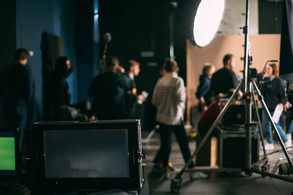 Actors and crew on a nighttime street set with production lights and a boom microphone held above the frame, creating a tense scene