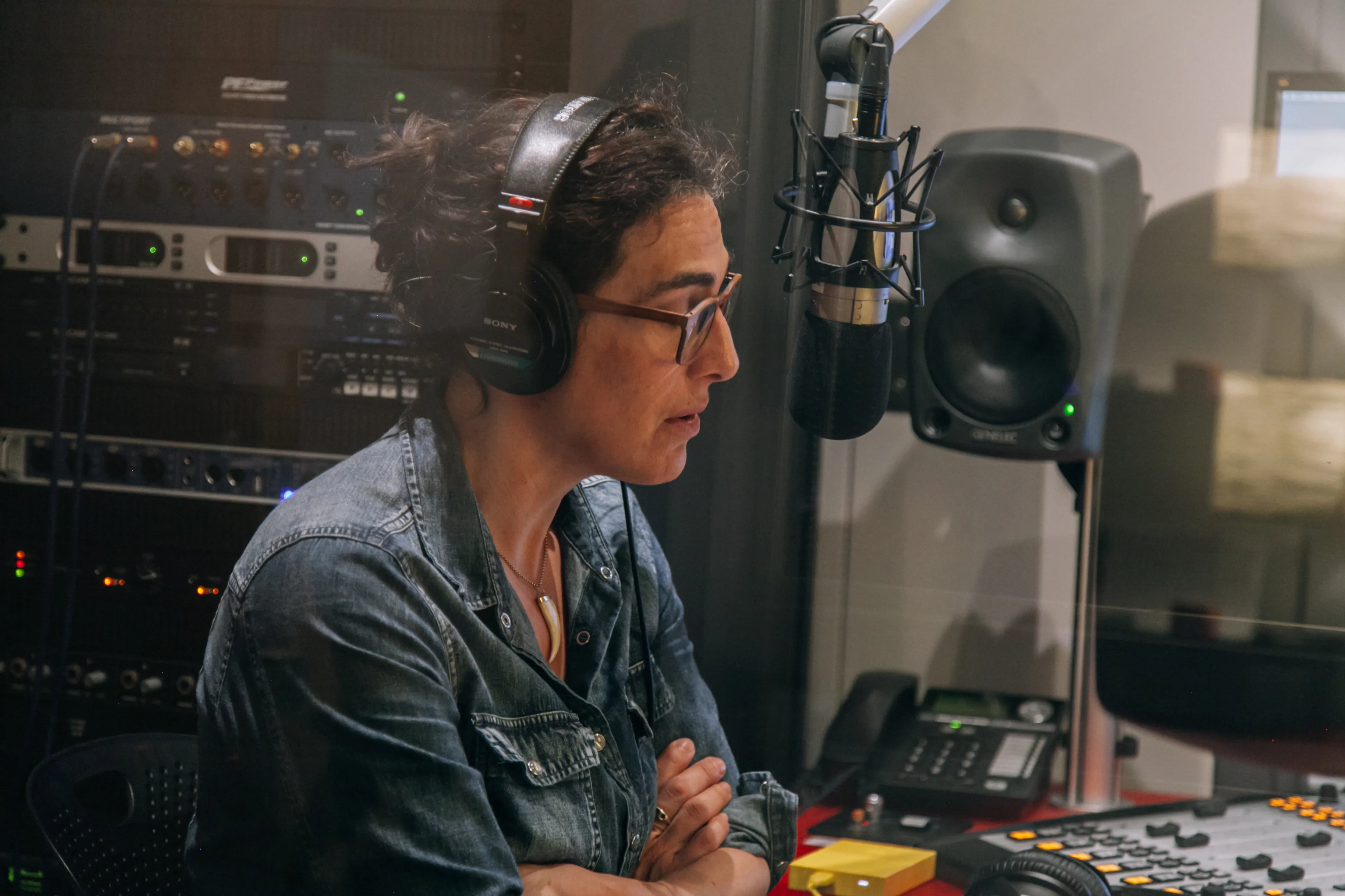 David Ridgen in a studio wearing headphones and speaking into a microphone